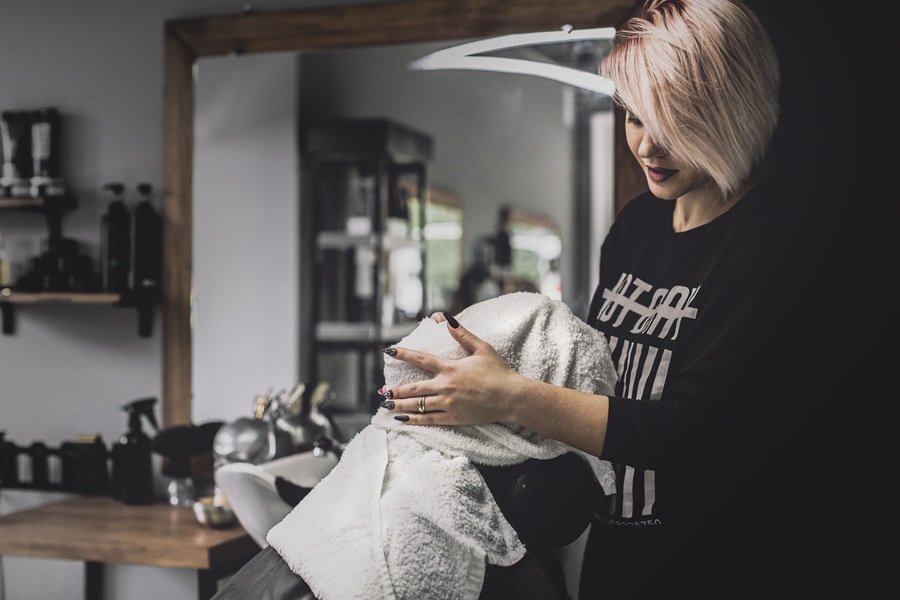 Website für Friseure - Friseurin im modernen Salon wickelt einem Kunden ein Handtuch um den Kopf – professionelle Haarpflege und Wohlfühlatmosphäre.